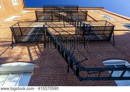 Bug Eye View Of Vintage Black Metal Construction Fire Escape Ladder With Makeshift Balconies And Acc