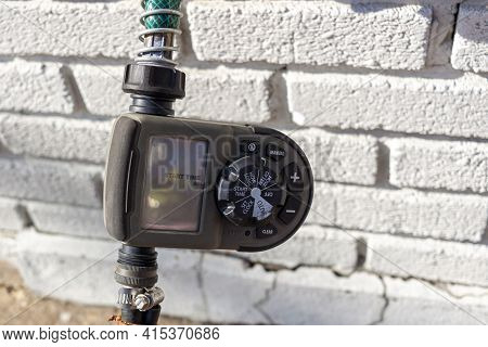 Alexandria, Va, Usa 11-28-2020: Close Up Digital Hose Timer Attached To Garden Hose Coming Out Of A 