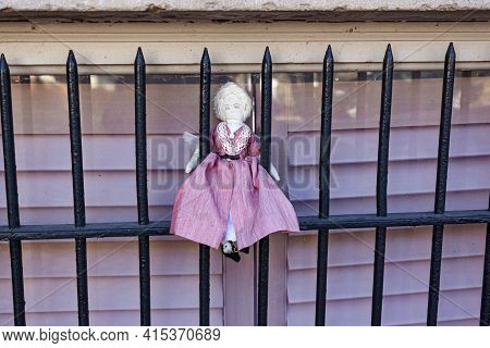 A Cute Straw Fabric Blonde Girl Doll Wearing Pink Vintage Folk Dress Is Attached On The Window Guard