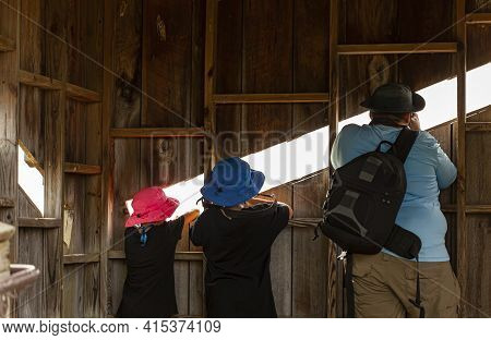A Man, His Two Kids Are In A Wooden Hide At A Wildlife Refuge Trying To Take Wildlife Images Through