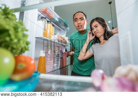 Dissapointed Couple While Opening The Fridge Door