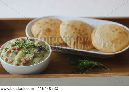 Deep Fried Indian Flat Bread Served With Mixed Vegetable Curry In A Coconut Cashew Gravy
