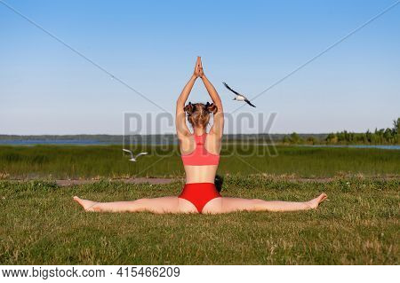 Backwards View Of Young Woman Practice Side Splits Or Samakonasana Yoga Pose At Nature On The Green 