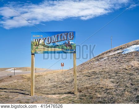 Cheyenne, WY, USA - April 2, 2021: Welcome to Wyoming - road sign with some stickers added by travelers, highway 85 in early spring scenery.