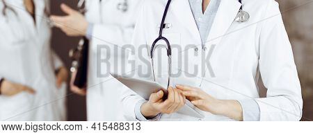 Unknown Woman Doctor Iusing Tablet Computer In Her Hands, While Standing In Clinic. Medicine Concept