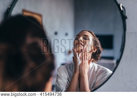 Woman In The Bathroom Washing Her Face With Foam