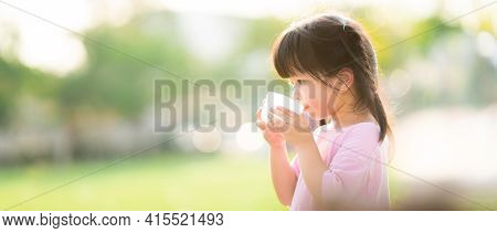 Concept Of Water Are Great For Kid. Child Are Drinking From Plastic Glasses. Natural Background. Dur