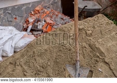 Close-up Of A Shovel Stuck In A Pile Of Sand On A Construction Site. High Quality Photo