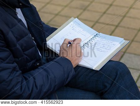 Business Diary Entry. A Man Makes Notes With A Writing Pen In A Business Diary. Notes In A Notebook.