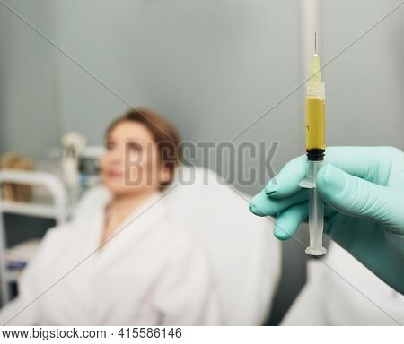 Syringe With A Patients Blood Plasma In A Cosmetologists Hand For A Plasmolifting Of A Womans Skin. 