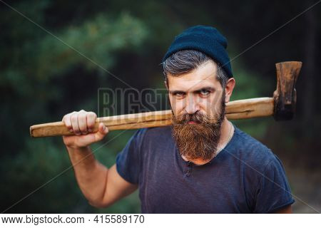 Severe Brutal Bearded Man In A Dark Sleeveless T-shirt With A Large Mustache And Gray Hair Holding A