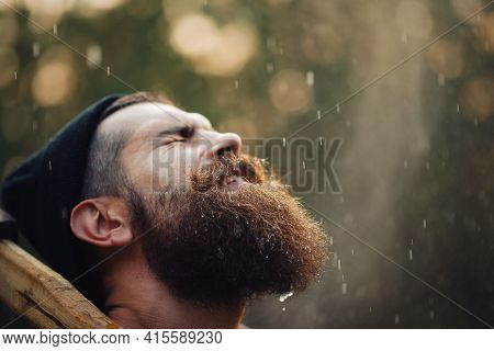 A Wet Bearded Man In A Dark Sleeveless T-shirt With A Large Mustache And Gray Hair Looks Up Into The