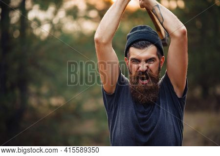 Angry Bearded Man With A Thick Beard And A Large Mustache In A Dark Sleeveless T-shirt And A Warm Ha
