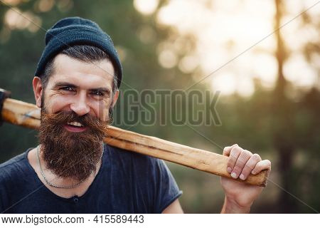 Laughing Adult Bearded Stylish Man In A Dark Sleeveless T-shirt And In A Warm Hat With A Large Musta