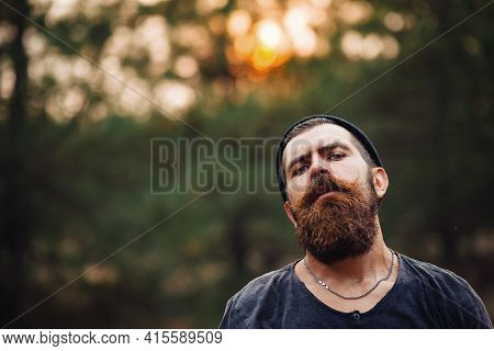 Man With Wet Beard In A Dark Sleeveless T-shirt With A Large Mustache And Gray Hair Looks Up Into Th