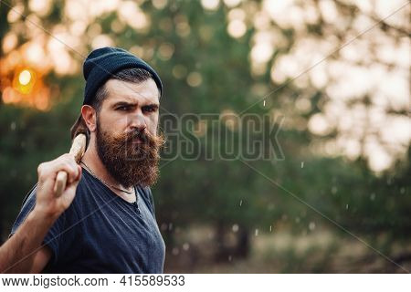 A Muscular Man With A Thick Beard And A Large Mustache In A Dark Sleeveless T-shirt And A Warm Hat W