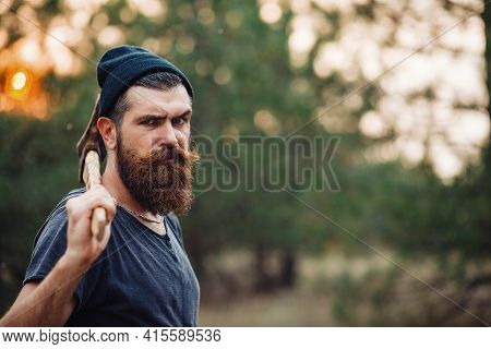 A Muscular Man With A Thick Beard And A Large Mustache In A Dark Sleeveless T-shirt And A Warm Hat W
