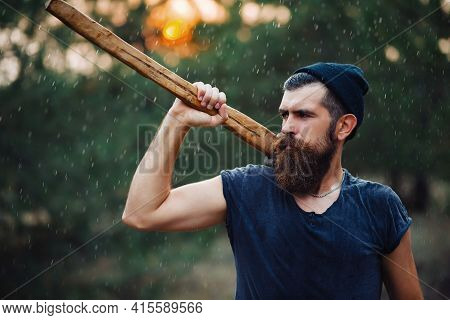 Lumberjack Man With A Thick Beard And A Large Mustache In A Dark Sleeveless T-shirt And A Warm Hat W