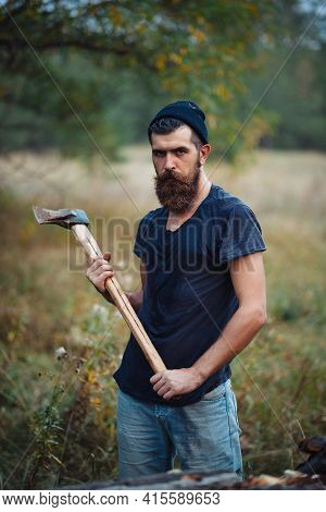 Brutal Man With A Thick Beard And A Large Mustache In A Dark Sleeveless T-shirt And A Warm Hat With