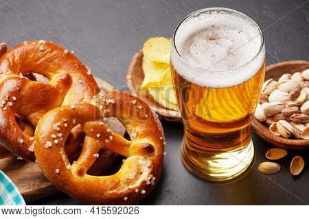 Lager beer mug, nuts, potato chips and fresh baked homemade pretzel with sea salt on stone table. Classic beer snack
