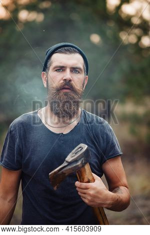 Stylish Brutal Bearded Man Lumberjack With A Long Beard And Mustache In A T-shirt And A Warm Hat Wit