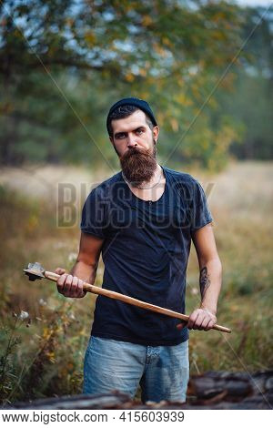 Stylish Brutal Bearded Man Lumberjack With A Long Beard And Mustache In A T-shirt And A Warm Hat Wit