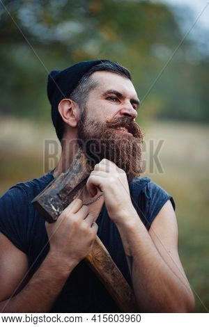Stylish Brutal Bearded Man Lumberjack With A Long Beard And Mustache In A T-shirt And A Warm Hat Wit