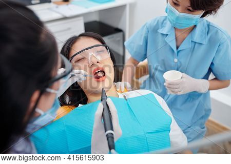 Dentist Drilling Teeth Of Young Female Patient Suffering From Teethache
