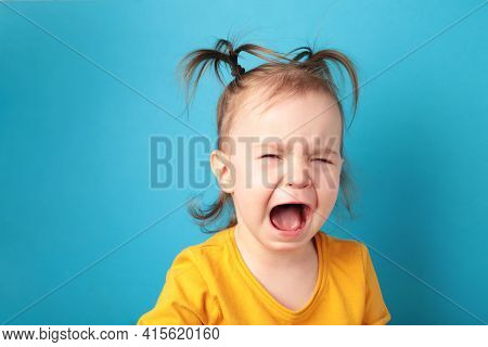 Upset Little Baby Girl Crying On Blue Background.