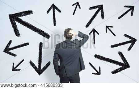 Businessman Standing Confused In Front Of A White Background With Black Arrows, Choice And Path Dile