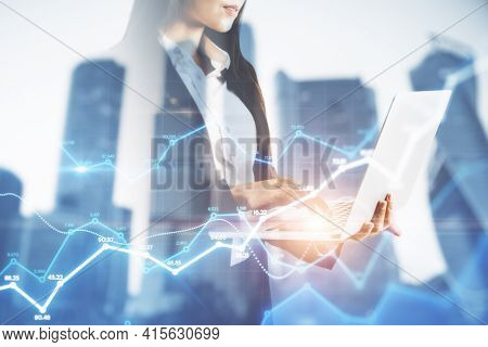 Businesswoman Holding A Laptop And Watching On The Holo Tading Charts, Background With City View, Ma