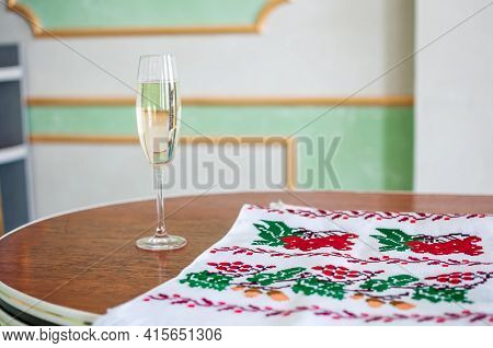 A Glass Of Champagne And An Embroidered Towel Stands On The Table