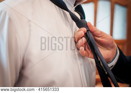 A Groomsmen Fastening Tie On The Grooms Neck