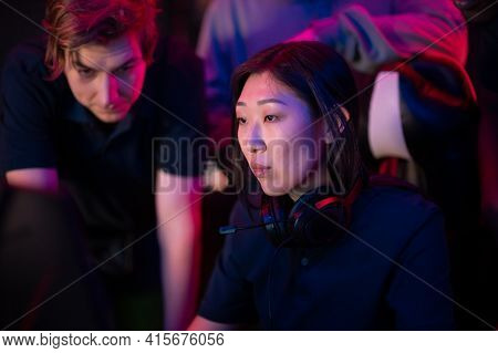 Asian Girl Playing In A Computer Club, Guys Standing Behind And Prompting