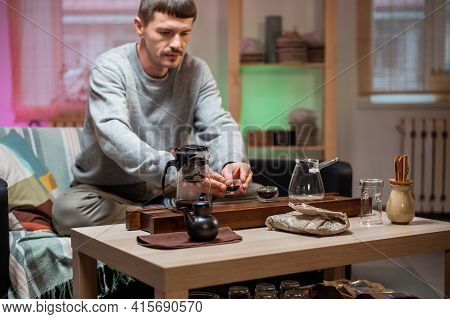 A Man Brews Chinese Tea According To An Old Oriental Recipe On A Bamboo Gongfu Tray. Adds Boiling Wa