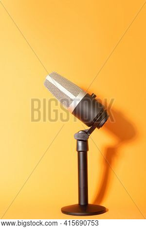 Professional Condenser Microphone With Pedestal Isolated On Orange Background Creating Shadow, Selec