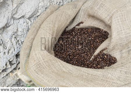 Close Up Image Of Canvas Sack Fuul Of Roasted Brown Coffee Beans Ready For Purchasing.