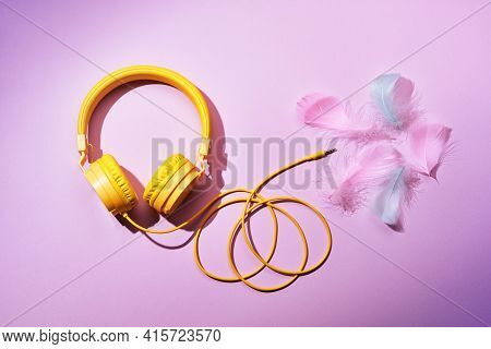 Yellow Headphones And Soft Feathers On Pink Background. Asmr Stress-relieving Sounds Concept, Flat L