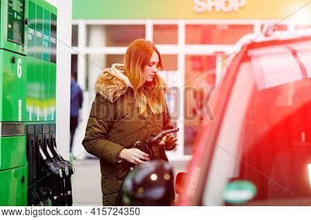 Young Caucasian Woman At Self-service Gas Station, Hold Fuel Nozzle And Refuel The Car With Petrol, 