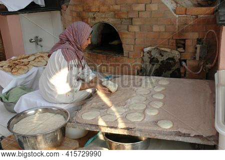 Cairo - OCTOBER 25: Egyptian Woman, prepares pita bread dough for baking in a traditional brick oven, Cairo, Egypt, October 25, 2008. Pita Bread is a staple in the Middle East. 