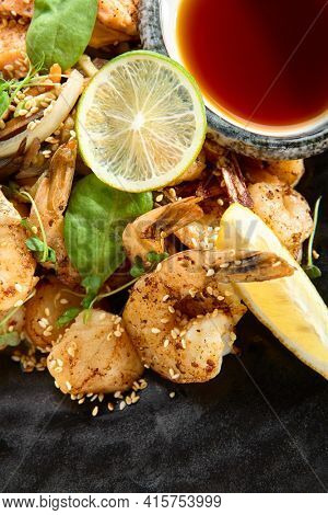 Teppanyaki Style Seafood - Grilled Mixed Seafood with Soy Sauce and Vegetables. Japanese Teppanyaki Salmon Steak, Shrimp, Scallop and Fish Fillet garnished with lemon and green salad. Top view