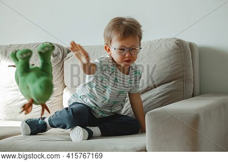 A Child With Autism In Glasses Sits On The Sofa And Sad, Angry A