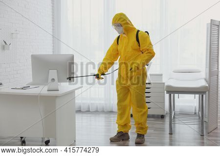 Employee In Protective Suit Sanitizing Doctor's Office. Medical Disinfection