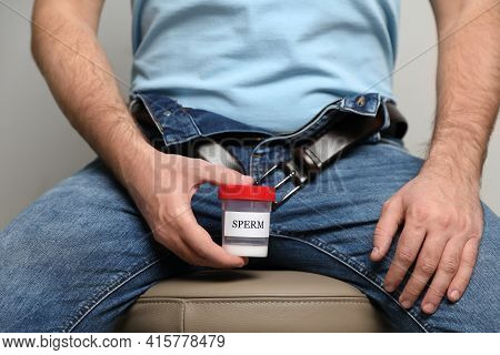 Donor With Unzipped Pants And Container Of Sperm Sitting On Stool, Closeup