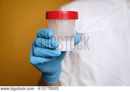 Scientist Holding Container With Sperm On Yellow Background, Closeup