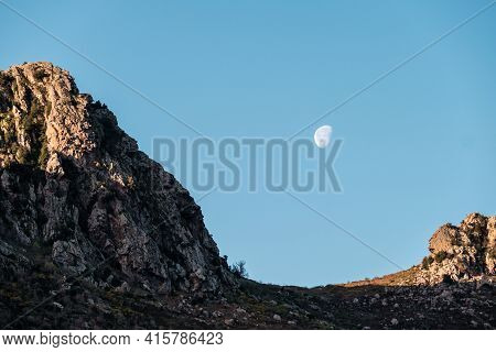 A Waning Gibbous Moon In The Eraly Morning Over The Rocky Mountains Of Corsica