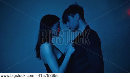 Side View Of Seductive Woman Touching Blazer Of Boyfriend On Blue.