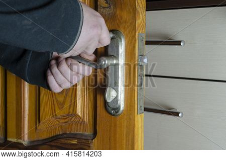 A Man Removes The Old Door Lock. Hands With A Screwdriver Unscrew The Mounting Screws Of The Mortise