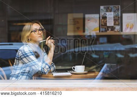 Young Beautiful Woman Working In A Cafe And Thinking. Online Courses. Freelance, New Normal Working.