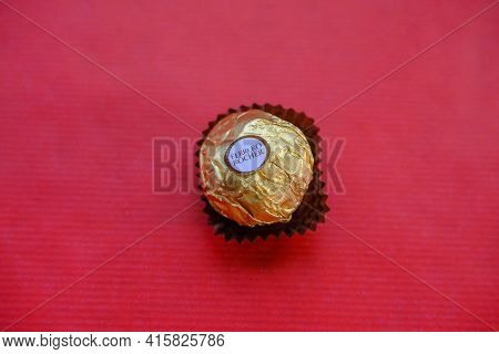 November 2020 Milan, Italy: Ferrero Rocher Chocolate On Red Background Top View. Ferrero Rocher Logo